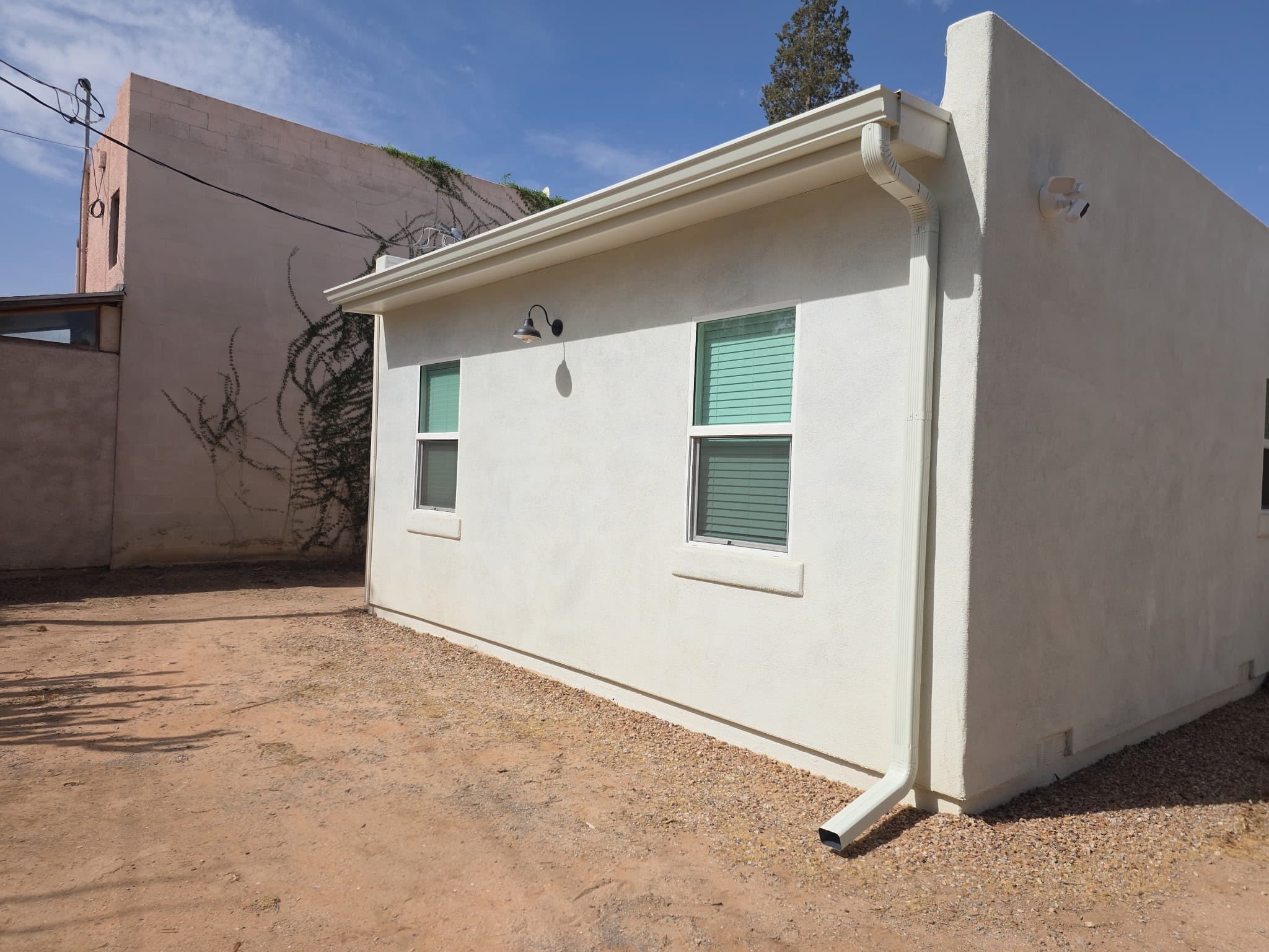 White aluminum seamless gutter and downspout cleanly installed on a Tucson stucco home
