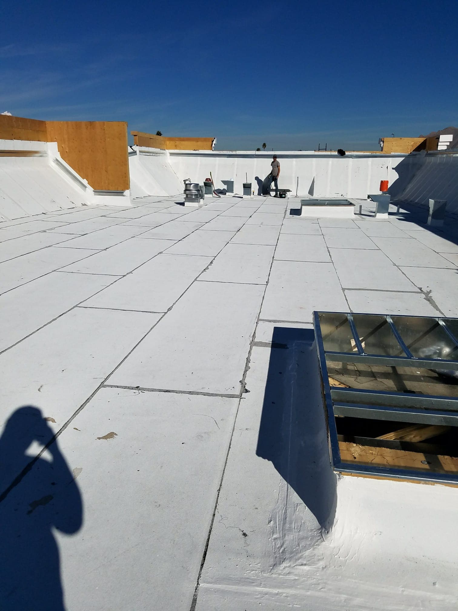Fresh white reflective coating — parapets and skylights cut in clean.