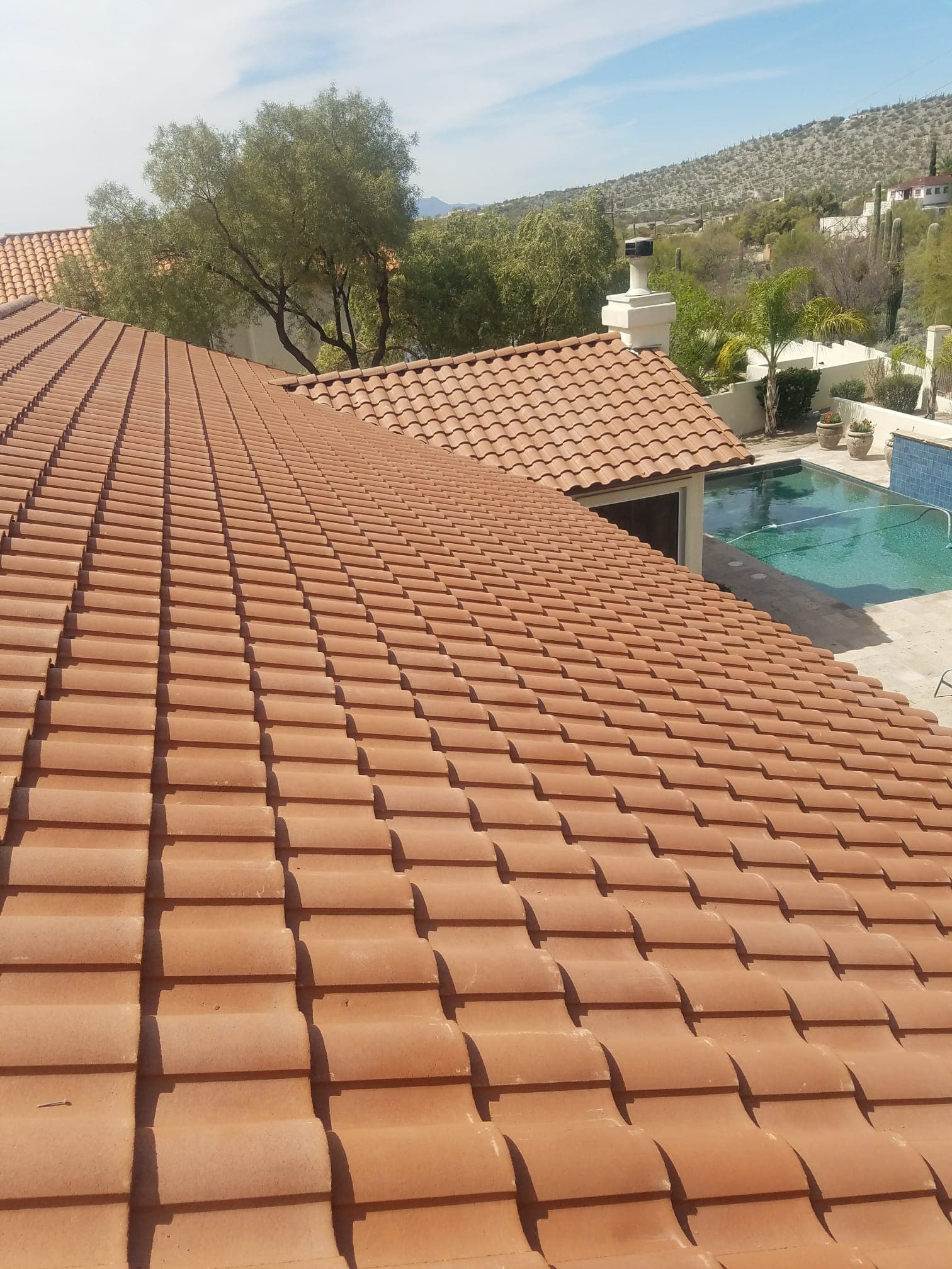 Finished Spanish-profile clay tile roof on a hillside Catalina Foothills home above a pool
